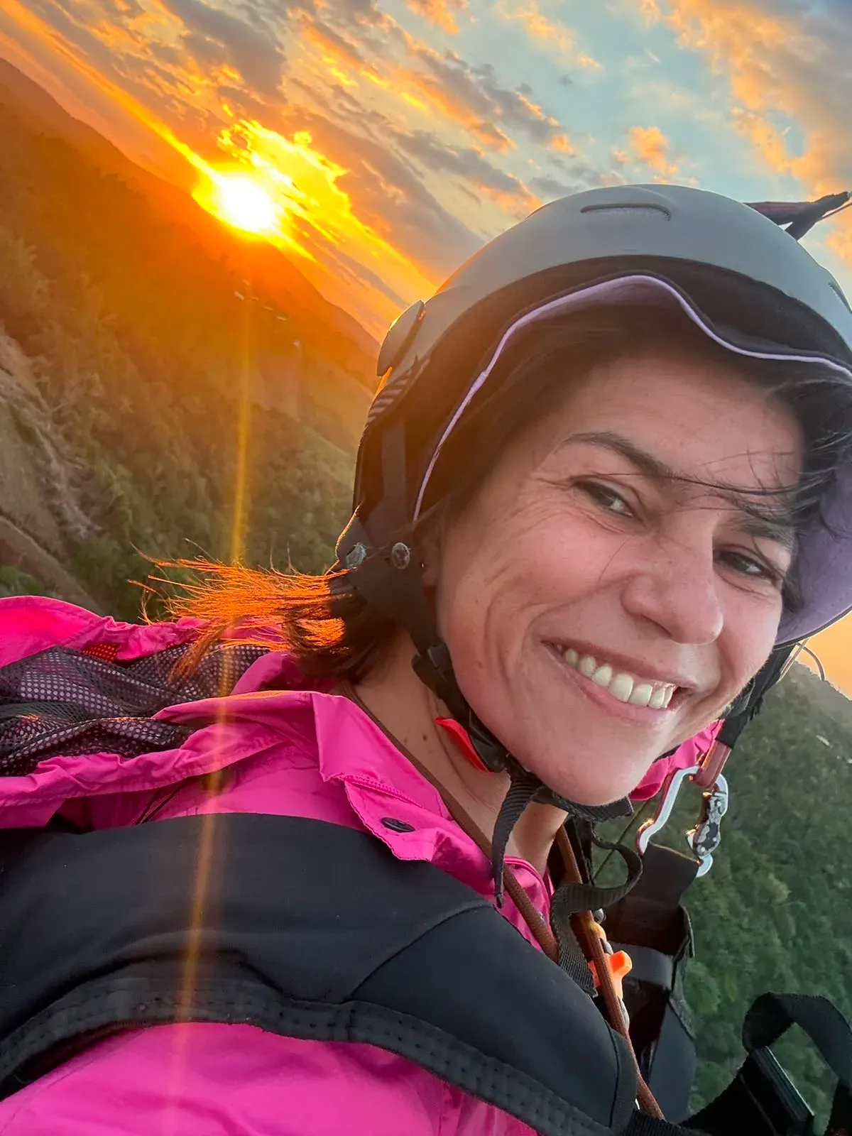 A paraglider in the air against a late-afternoon sky